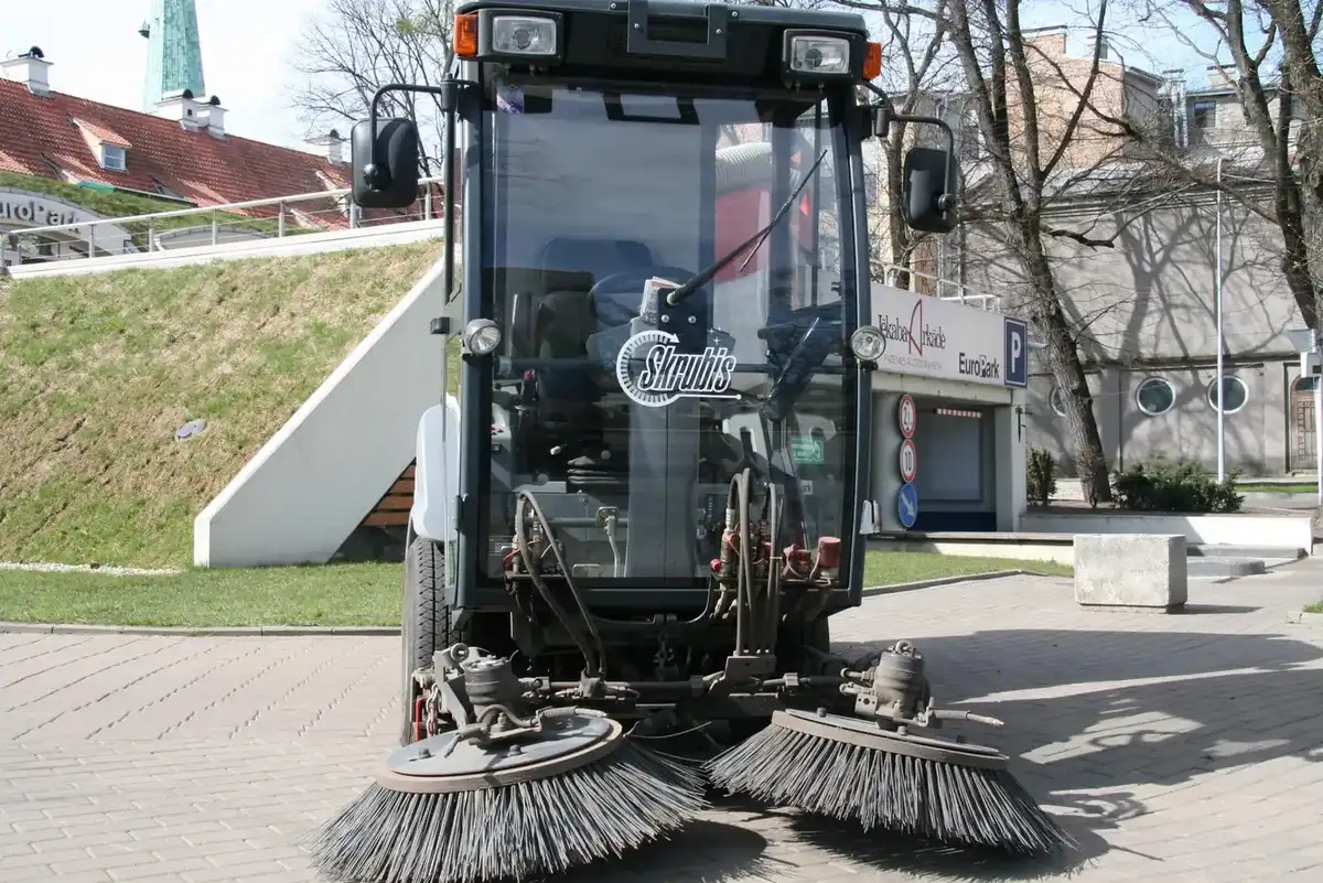Подметальная машина Skrubis с двумя боковыми щётками убирает мощёную площадь у парковки EuroPark